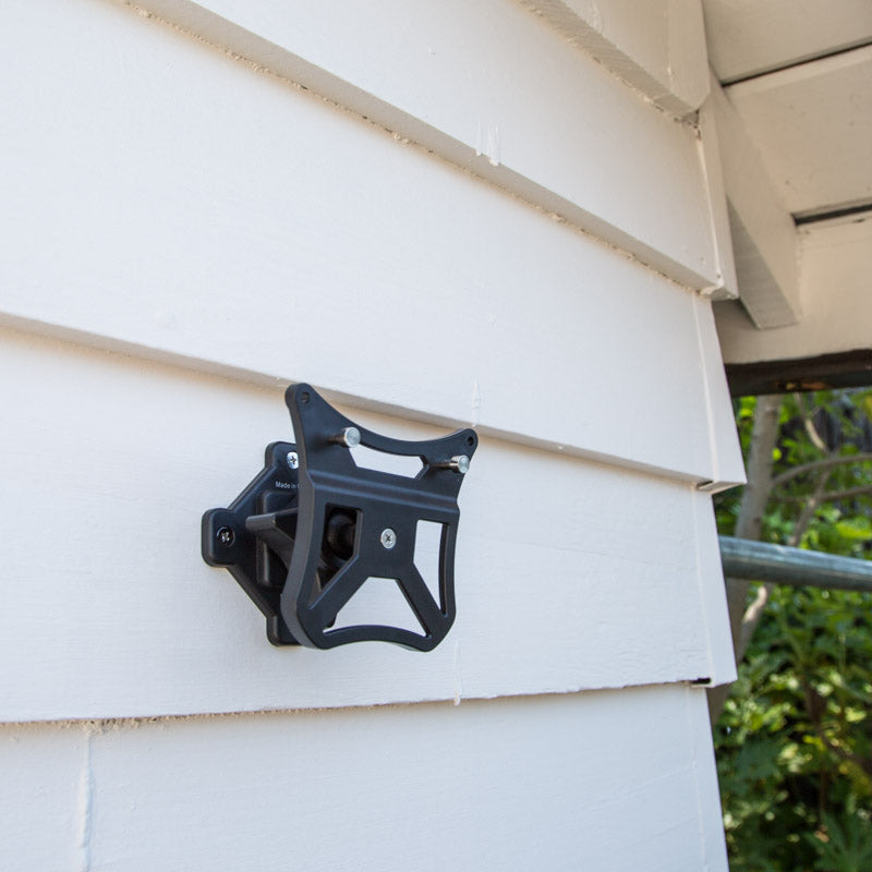 Solar Pack MAX mounting bracket installed on a house with white siding